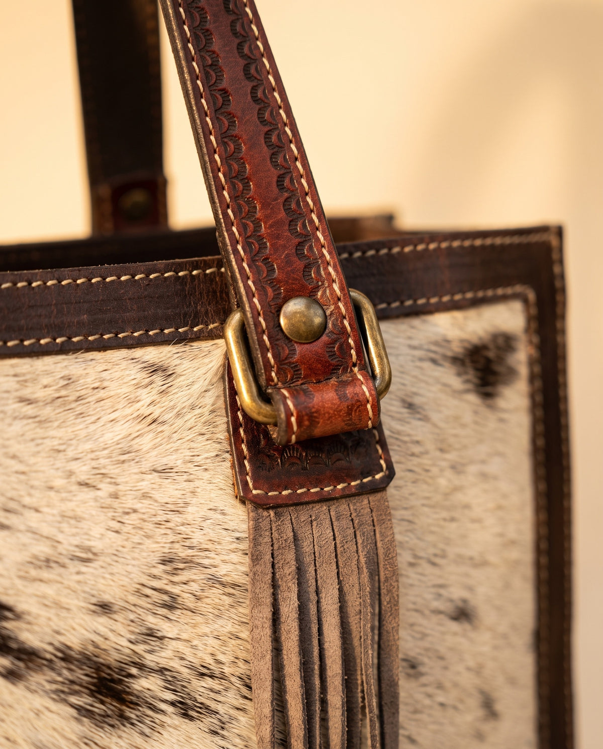 Dark brown tooled triangle hair-on cowhide leather tote with fringe, handle and fringe close-up, by Ya Qalbi