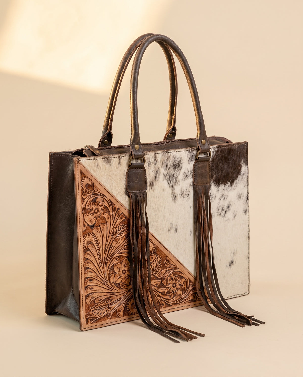 Tan tooled triangle hair-on cowhide leather tote with fringe, angled view, by Ya Qalbi